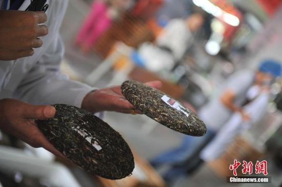 工作人員展示壓好的普洱茶茶餅。中新社記者 劉冉陽 攝